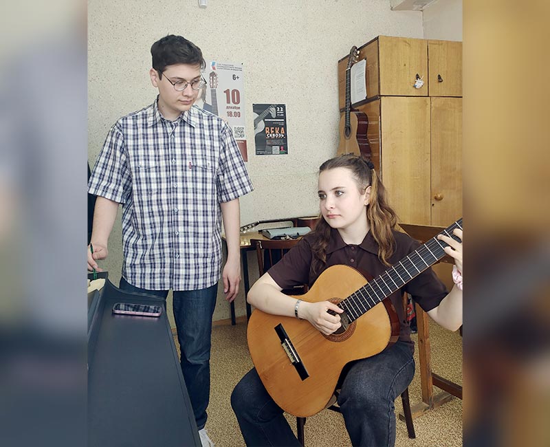 Она берет в руки гитару…