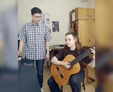 Она берет в руки гитару…